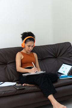 Woman telecommuting from sofa using digital tablet