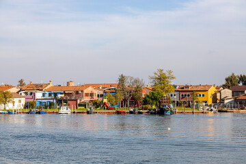 Obraz premium View of Burano's colorful waterfront houses and moored boats, seen from Mazzorbo, Venice, Italy