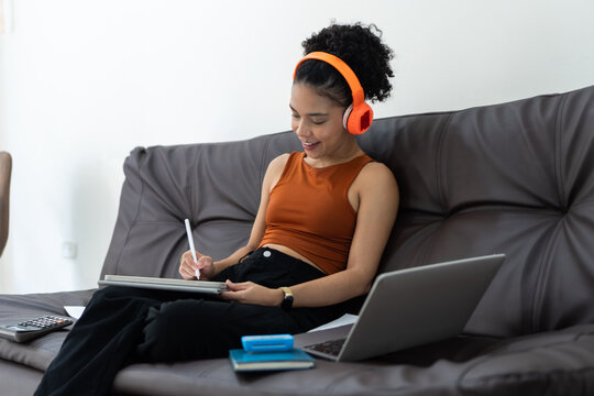 Woman working from home using digital tablet with headphones