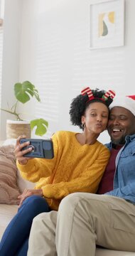 Vertical video: African American couple taking selfie on couch, scrolling phone sharing surprise