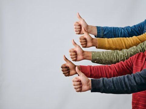 Four Diverse Hands Raised in Unity Giving Bright Thumbs-Up Against Minimalist Light Gray Background