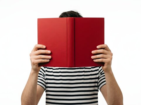 Person Concealed Behind a Bold Red Hardcover Book Held in Front of a Striped Shirt Against Plain White Background