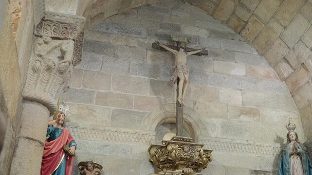 Carved Crucifix Between Painted Statues Of Saints On A Bare Granite Church Wall