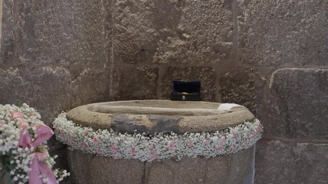 Old Granite Baptism Font Ringed With White Gypsophila And Pink Roses Beside A Candle