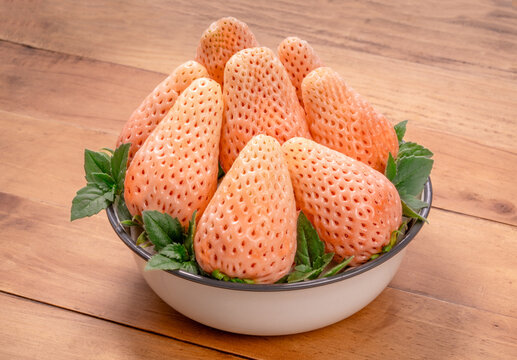 Sweet Pink snow Strawberries on wooden Background, Pink snow strawberry in white plate on wooden background.