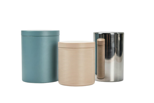 Three cylindrical storage containers in matte blue, ribbed beige, and reflective metallic silver finishes isolated on a transparent background