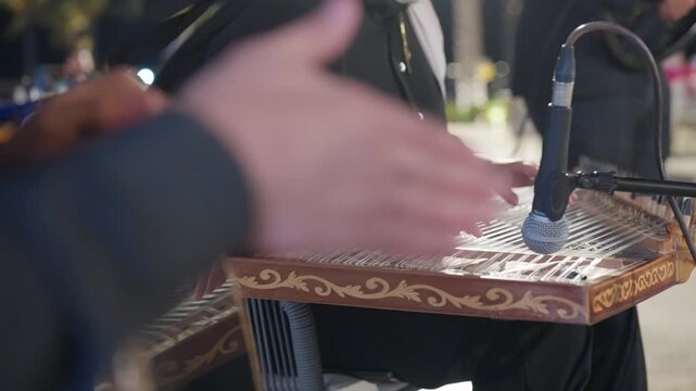 Professional musicians performing live traditional middle eastern music using qanun and darbuka instruments during an outdoor event.