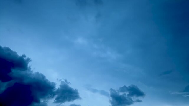 Dramatic time lapse footage of dark storm clouds moving across blue evening sky.