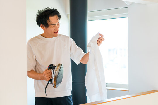 自宅でアイロンがけをする中年男性