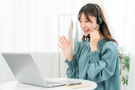 A woman using a computer with a headset on; a businesswoman.