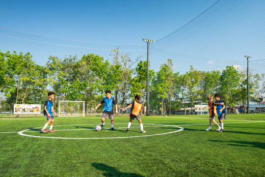 Two teams of kid football players competing during soccer game on sports field.