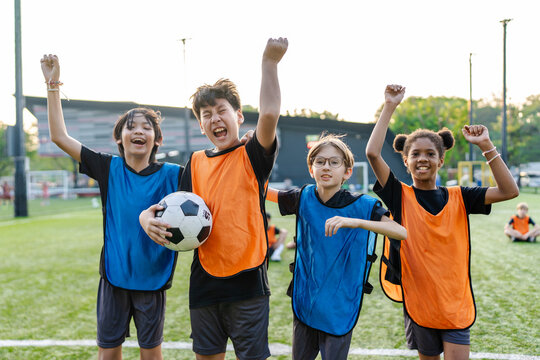 Portrait of diverse kid football players celebrating victory together.