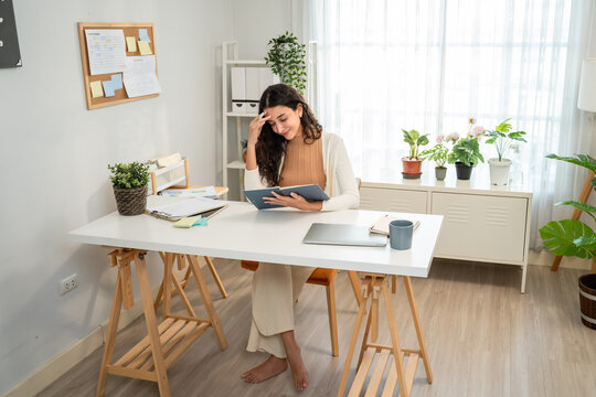 Hispanic woman quietly reading a book while sitting on working table. 