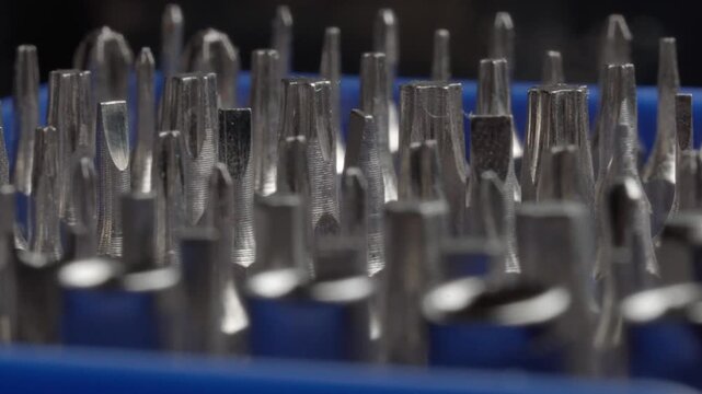 Macro close up of assorted metal screwdriver bits arranged in blue tool holder, showing different tip shapes and sizes for hand tool repair and maintenance work