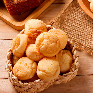 Homemade Brazilian cheese bread served on a wooden platter, accompanied by fresh Minas cheese, butter, and black coffee