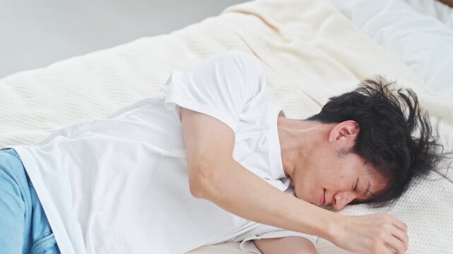 ベッドに寝る男性。疲れ、疲労、昼寝、ライフスタイル、寝室、落ち込む、あくび、寝不足、不眠症、眠る