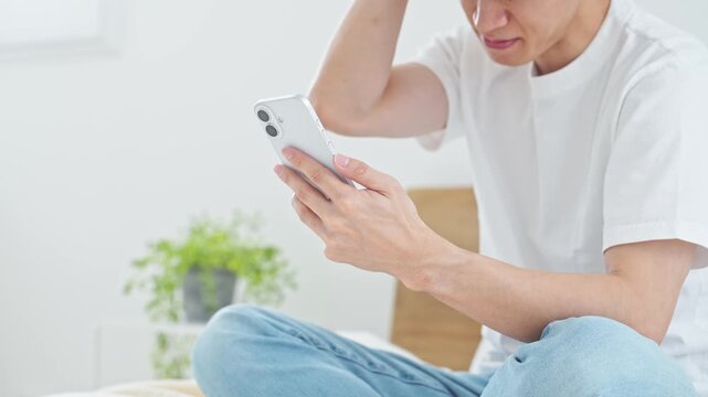A man using a smartphone in bed. Apps, social media, mistakes, trouble, worries, feeling down, disappointment, regret, videos, online backlash.