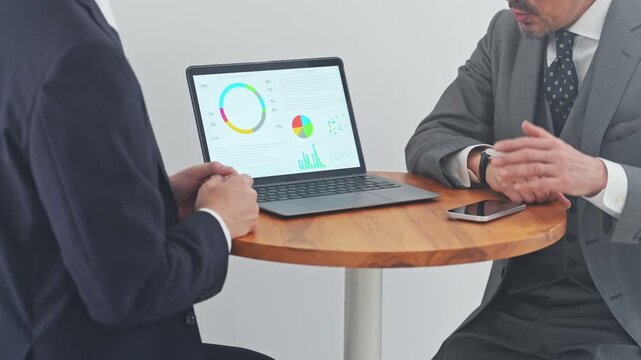 Business professionals conversing while looking at a laptop. Sales, proposals, meetings, marketing, graphs, analysis, research.