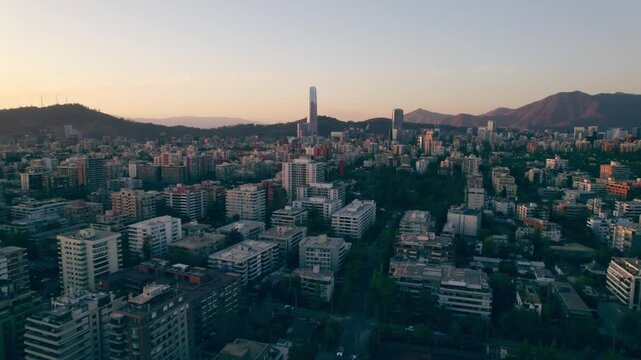 Aerial view of Santiago city skyline during golden hour with Gran Torre Santiago skyscraper and Andes mountains.