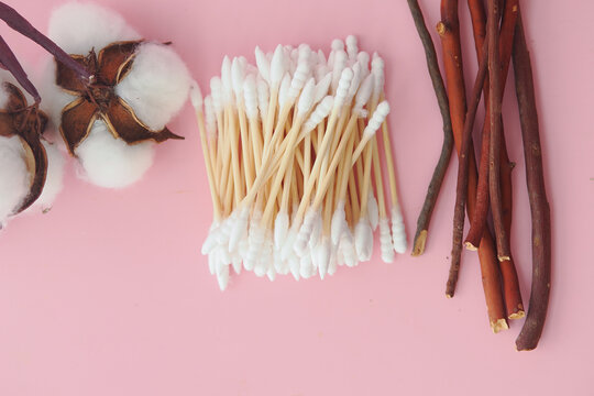 Natural Cotton Swabs and Cotton Bolls on Pink Background With Wooden Sticks and Twigs