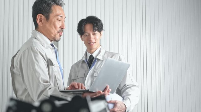 打ち合わせする男性作業員のグループ。建設、工事、工場、業者、相談、会議、DX、修理、点検、建築、内装