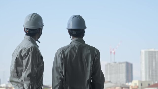 建設中の都市を眺める男性作業員のグループ。工事、チームワーク、安全、点検、建築、現場、ビルメン、検査