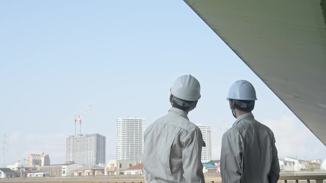 建設中の都市を眺める男性作業員のグループ。工事、チームワーク、安全、点検、建築、現場、ビルメン、検査