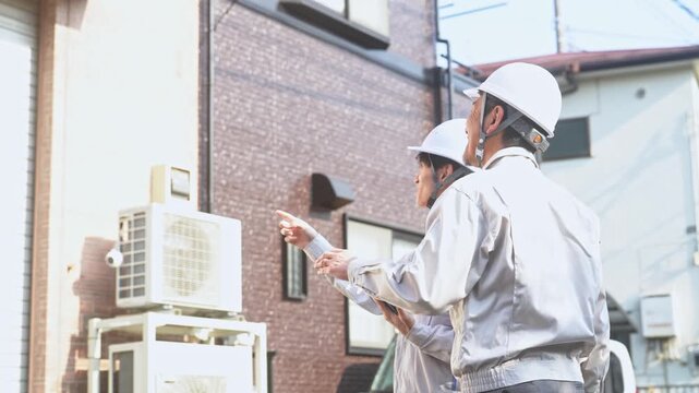 住宅を点検する男性作業員のグループ。建築、工事、外壁、修繕、修理、保守、メンテナンス、チームワーク