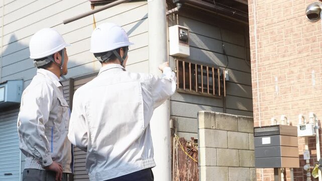 住宅を点検する男性作業員のグループ。建築、工事、外壁、修繕、修理、保守、メンテナンス、チームワーク