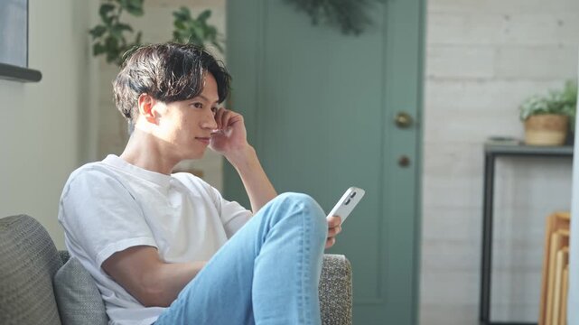 スマホを使う男性。アプリ、SNS、動画、メール、DX、ゲーム、リラックス、若者、検索、スマートフォン