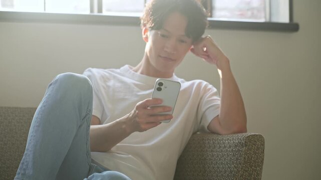 スマホを使う男性。アプリ、SNS、動画、メール、DX、ゲーム、リラックス、若者、検索、スマートフォン