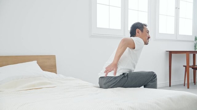 腰痛に悩むシニア男性。ぎっくり腰、ミドル、中高年、老化、加齢、痛み、困る、ヘルニア、ベッド、健康