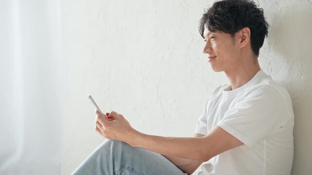 スマホを使う男性。アプリ、SNS、動画、メール、DX、ゲーム、リラックス、若者、検索、スマートフォン