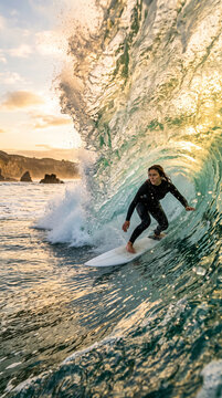 Surfeuse glissant dans un tube de vague au coucher du soleil