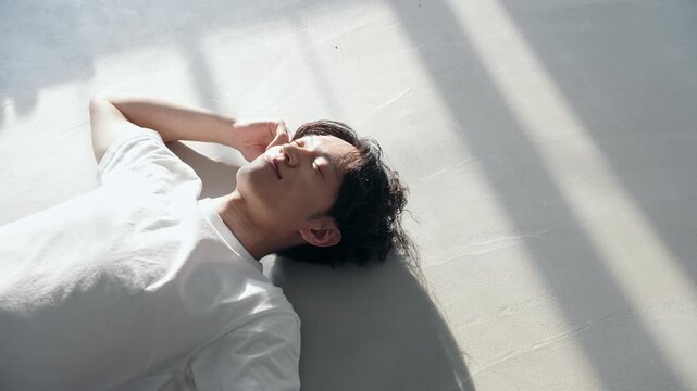 床に寝転ぶ男性。リラックス、休憩、休日、のんびり、美容、メンズビューティ、くつろぐ、イケメン、昼寝