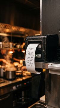 Imprimante de caisse sortant un ticket de commande dans la cuisine d'un restaurant en service