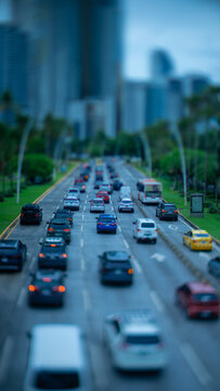 Tilt shift view of rush hour traffic on a wide palm lined city avenue