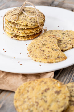 Rustic treat. Tasty cookies. Home savory biscuits baked with seeds served on white plate. Pile tied with rope together on wooden table.
