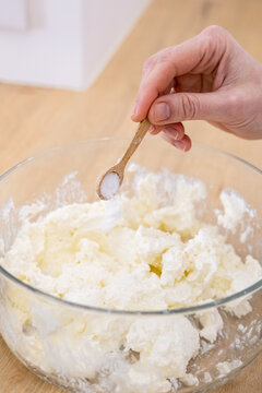Culinary recipe. Preparing dish. Female chef measuring ingredient adding salt sugar flour in glass bowl with cottage cheese dough.
