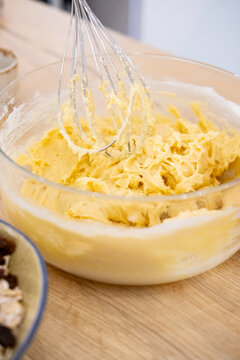 Dough preparation. Home cuisine. Kitchen metal whisk mixing thick yellow butter pastry recipe mass in glass bowl on culinary countertop.