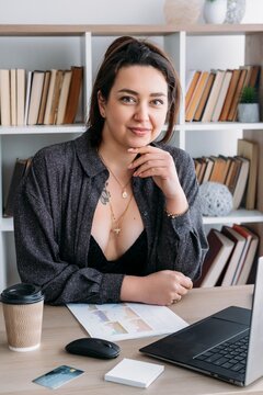 Business routine. Office lifestyle. Smiling relaxed woman at desk with laptop notes preparing for paperwork document at modern workplace.