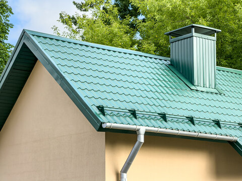 green metal tile roof with gutter, drainpipe and chimney.