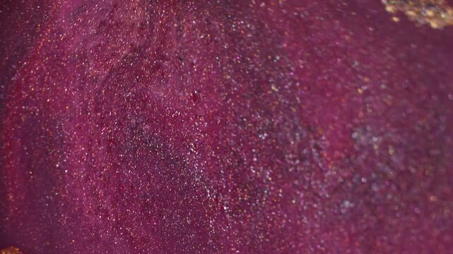Shimmer ink. Fluid mix. Defocused yellow purple golden color acrylic glitter particles floating on abstract creative art background.