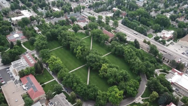 Aerial view of lush green university campus quadrangle featuring walking paths and surrounding trees in summer.
