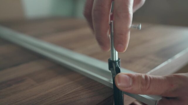 Close-up of hands threading a bolt into a white flat-pack furniture panel during assembly