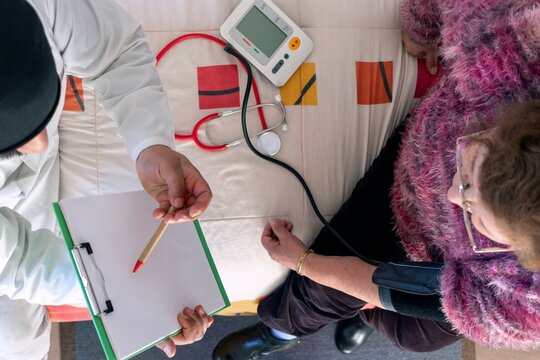 Doctor checking elderly woman's blood pressure at home