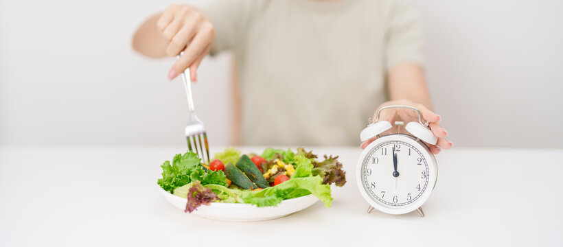 happy smiling woman with fresh organic vegetables plate and alarm clock. intermittent fasting, IF, meal time, nutrition, weight loss, clean eating, Healthy food eating, Wellness, dieting and lifestyle