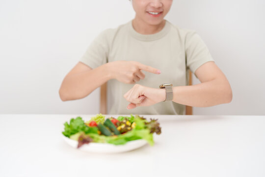 happy smiling woman with fresh organic vegetables plate and checking time. intermittent fasting, IF, nutrition control, weight loss, clean eating, Healthy food eating, Wellness, dieting and lifestyle