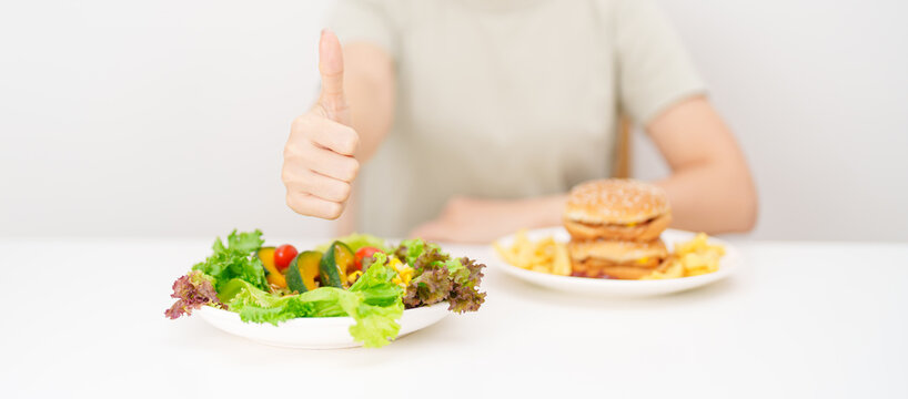 happy woman choose vegetables Salad and thumbs up gesture. Healthy and Unhealthy Food Choice, Calories and Nutrition of vegetables and Hamburger. dieting, weight loss control, junk food and lifestyle