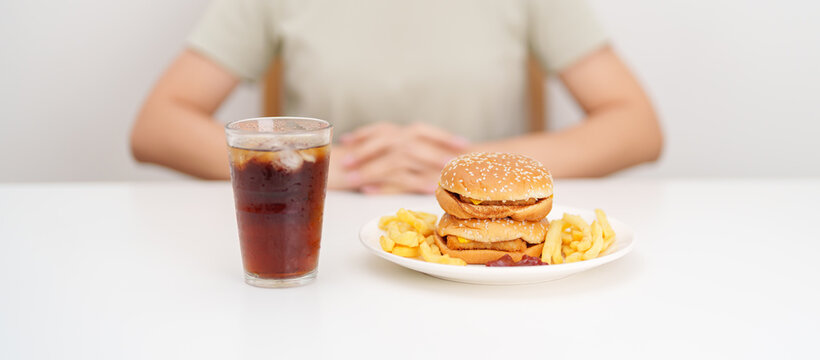 happy woman with Juicy beef burger with melted cheddar cheese, potato chips and carbonated Soft drinks. Unhealthy, High calorie, Fast food craving, Obesity, diet, weight loss, junk food and lifestyle